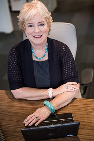 April Burke sitting at a desk, smiling