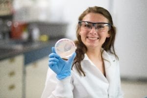 BTI summer intern holding up a petri dish in the lab