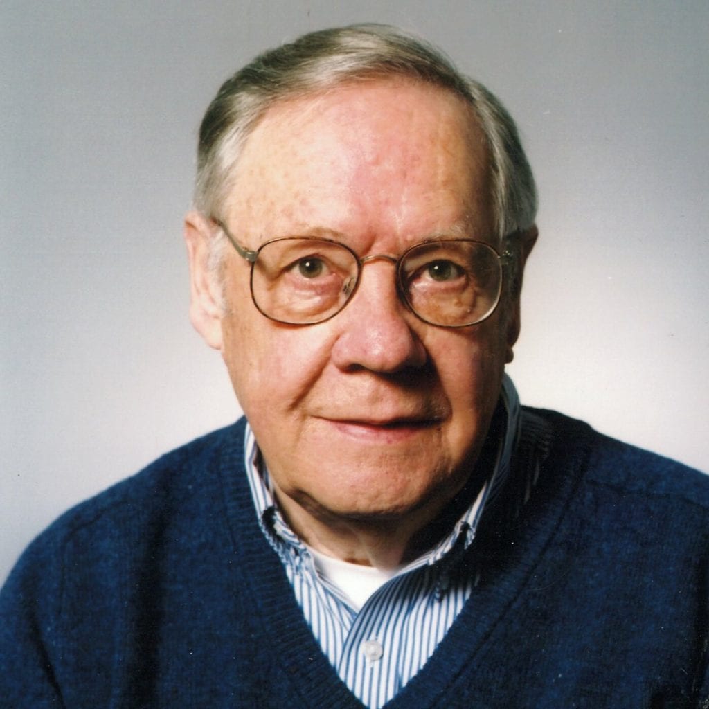 Close up picture of Dick Staples in a dark blue sweater over a light blue collared shirt.