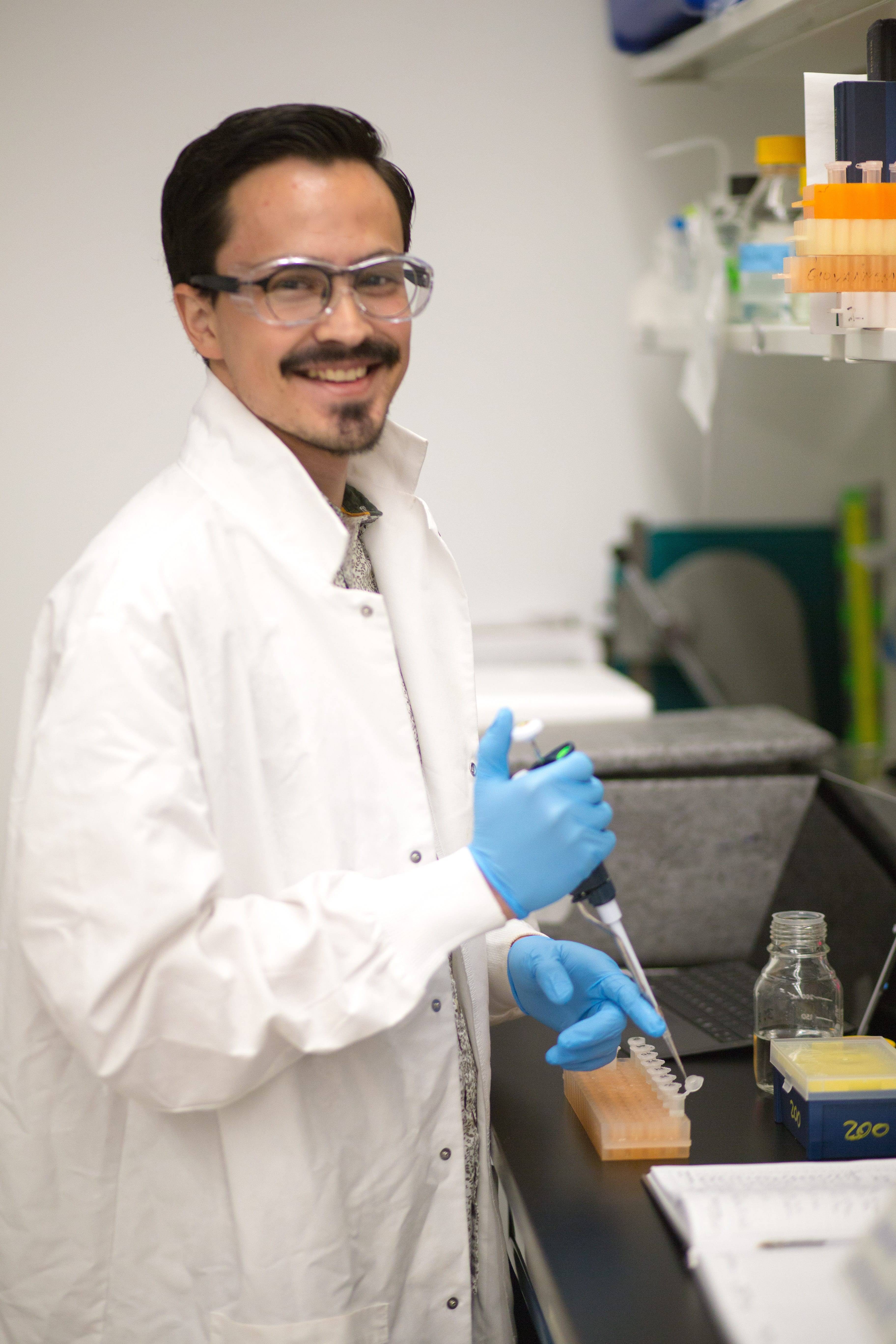 Scientist smiling and holding a pipette in a lab