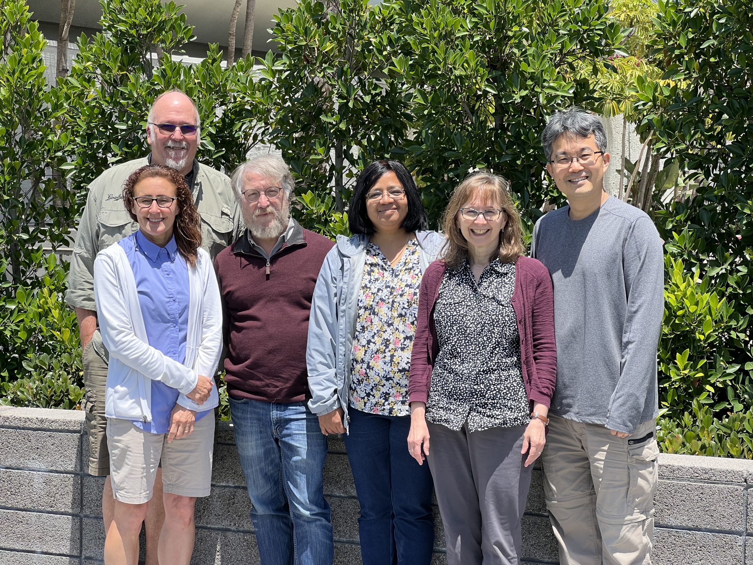 A group photo of, from left to right, Heidi Kaeppler, Bill Gordon-Kamm, Wayne Parrott, Veena Veena, Joyce Van Eck and Keunsub Lee. They are standing outside in front of a green bush.