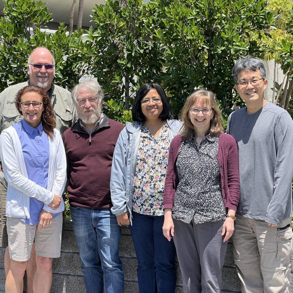 A group photo of, from left to right, Heidi Kaeppler, Bill Gordon-Kamm, Wayne Parrott, Veena Veena, Joyce Van Eck and Keunsub Lee. They are standing outside in front of a green bush.