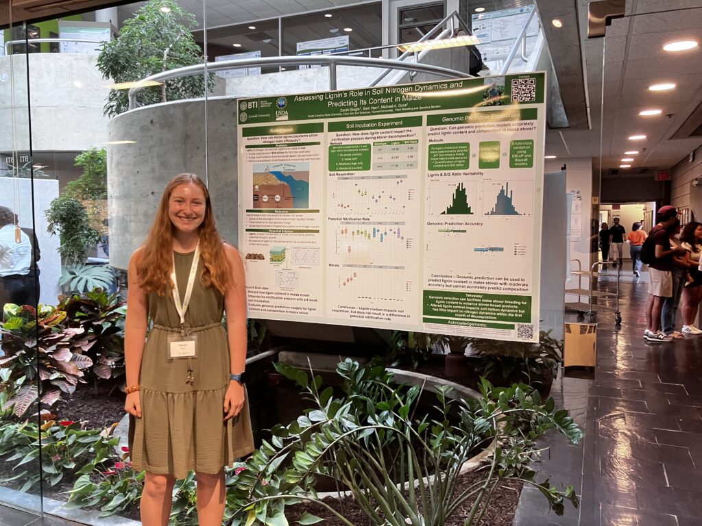 Sarah standing in front of her poster at the Symposium
