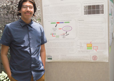 Miguel Barrera stands with his poster at the poster session